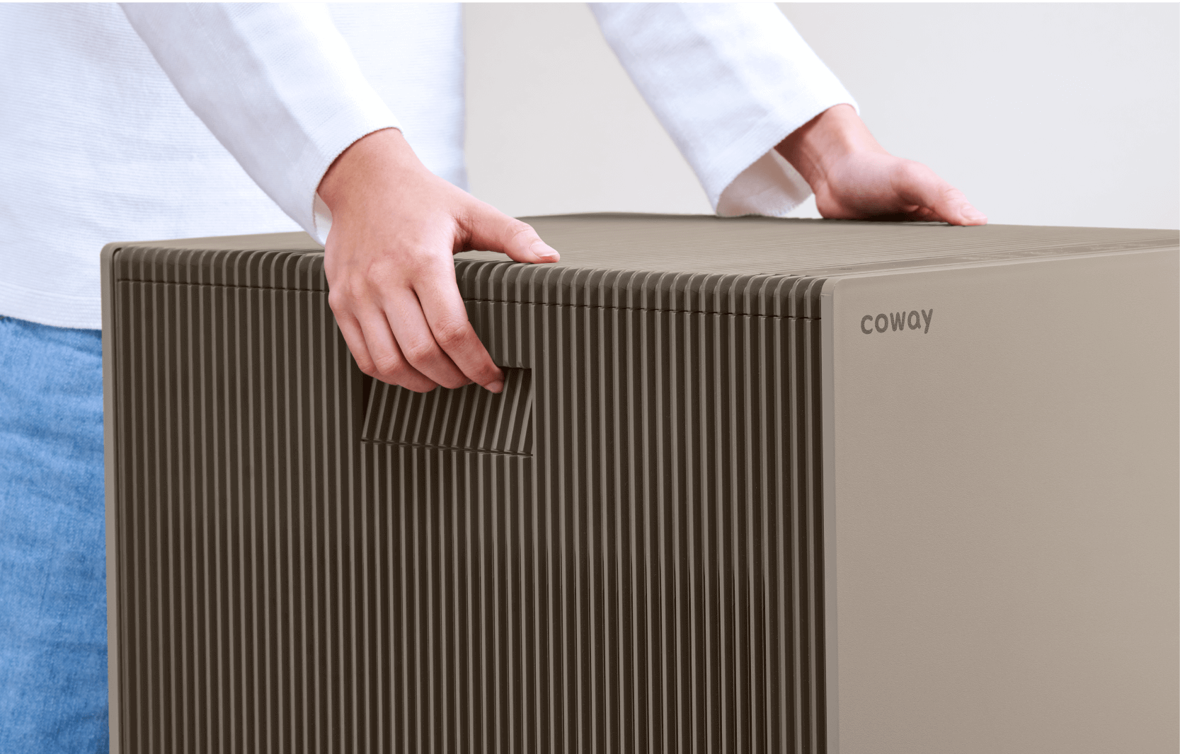 A hand lifting the Coway Atrium by its concealed side handle