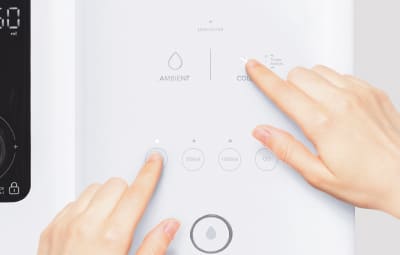 Two hands operating the Coway Ombak touch panel