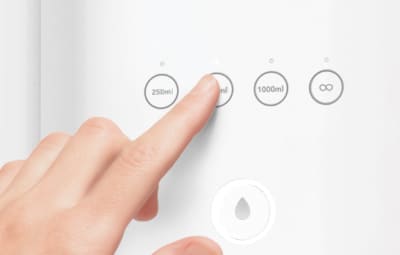 A finger selecting a water volume preset on the Coway Ombak