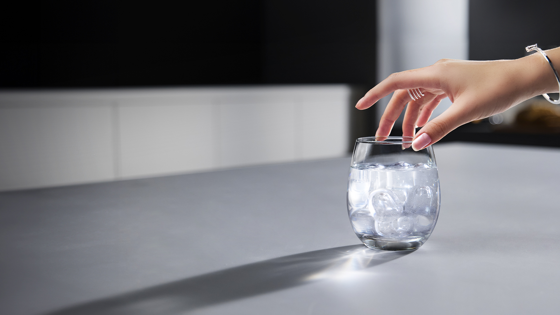 A glass of crystal-clear water filled with Coway Ais bullet ice on a counter